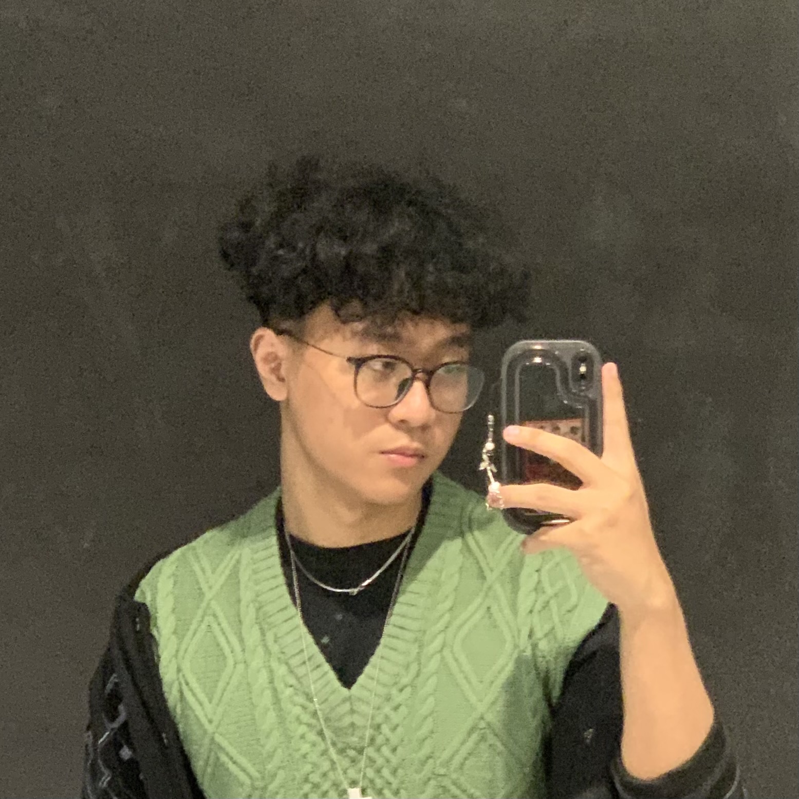 Hamza Pratama taking a mirror portrait, wearing a green knit vest